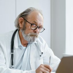 Healthcare worker looking stressed at computer illustrating why staff wellbeing programs focused only on individuals fail to address systemic burnout